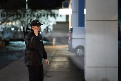 Security guard on patrol shining his flash light into the building exterior